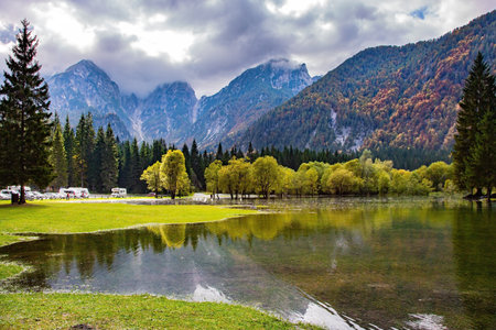 Picturesque lake Fusine in Northern Italy. The smooth surface of the water reflects the surrounding forests and mountains. Mountains covered in morning mistの写真素材