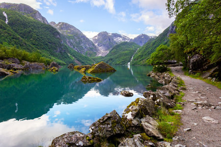 Picturesque mountain lake Bondhuswatnet. Gorgeous mountainous Norway. Evening soft twilight. The smooth surface of the clear lake water reflects the mountains.の写真素材