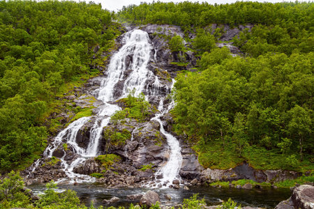 Summer trip to the north of Europe. Vertical waterfall Flesefossen on the most picturesque road in Norway. The mountain slopes are overgrown with green forests.の写真素材