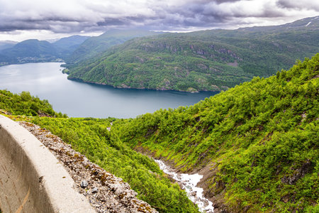 Magnificent panorama of the fjord. Norway. Traveling by camper on road 520. The road is fenced with a concrete fenceの写真素材