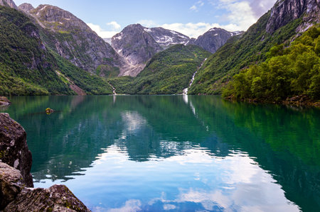 Picturesque mountain lake Bondhuswatnet. Gorgeous mountainous Norway. The smooth surface of the clear lake water reflects the mountains. Evening soft twilight.の写真素材