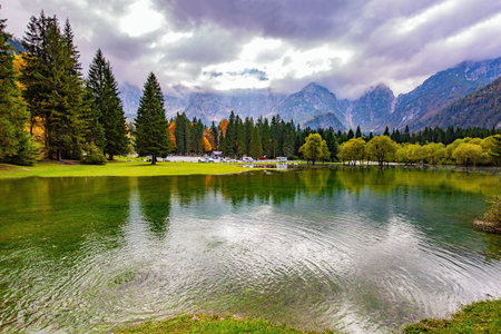 Picturesque shallow lake Fuzine of glacial origin. The mountains are covered with low clouds. The lake shores are flooded. Wonderful autumn dayの写真素材
