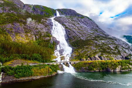 Western Norway. Langfossen is a magnificent huge and powerful cascading waterfal on the Vaule River. Passes through the highway. Filmed with a droneの写真素材