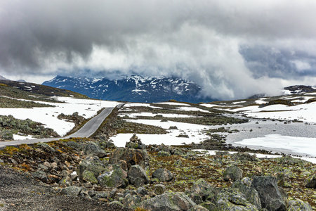 Gorgeous picturesque "Snow Road". Huge cold snowfields and sharp stone placers. Low gray clouds and fog. Summer trip to Norway. Cold July in Northern Europeの写真素材