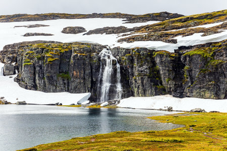 Frozen lakes and waterfalls. Cold July in Northern Europe. Gorgeous "Snow Road". Huge cold snowfields and sharp stone placers. Summer trip to Norway.の写真素材