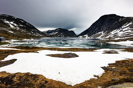 Semi-frozen lake Djupvatnet in the mountains of Northern Norway. Frozen lakes and waterfalls. Summer trip to Norway. Cold July in Northern Europe.の写真素材