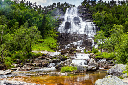 The colossal roaring waterfall Twindefossen. Summer day in the mountains of Norway. Exciting adventure in the north of Norway. Travel north. Picturesque green country in summer.の写真素材