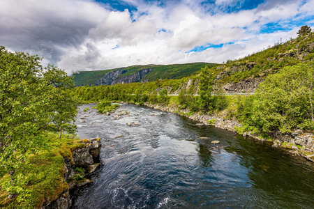 The western Norway. The seething waterfall - threshold on the river Bioreio. The green shores are reflected in the smooth water. The interesting trip to the Scandinavian.の写真素材