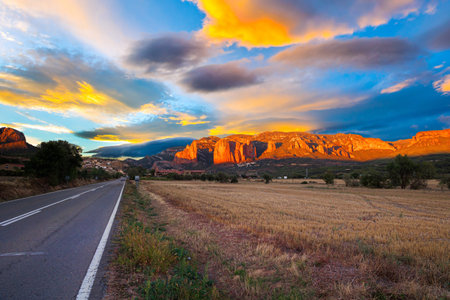 Red sunset. The magnificent Mallets of Riglos cliffs. Scenic paved highway. Romantic trip to Spain. Province of Huesca, Aragon. Mallets of Riglos is a conglomerate of rock formations.の写真素材