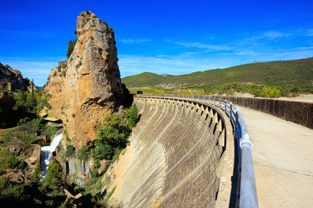 Magnificent dam collects the waters of the Gallego River into the La Penia Reservoir. Picturesque conical rocks over the reservoir. Province of Las Penias de Riglos. Spain.の写真素材