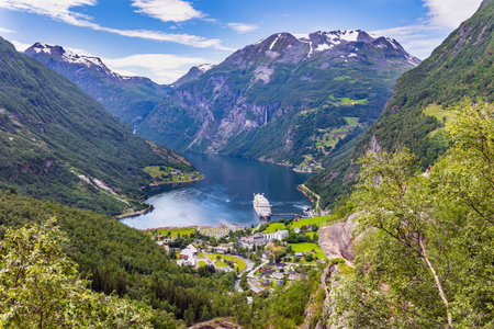 The largest, most beautiful and famous Norwegian fjord Geiranger. Snow-white ocean liner is moored at the pier. Warm sunny day in July. Summer trip to Norway.の写真素材