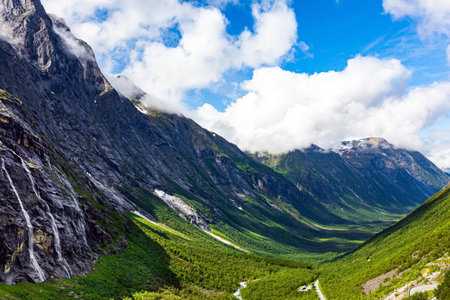 Bright picturesque shadows on the green grassy slopes of a giant canyon. Sunny summer day in the mountains of Norway. Photo taken from a drone. The famous "Troll Staircase" .の写真素材