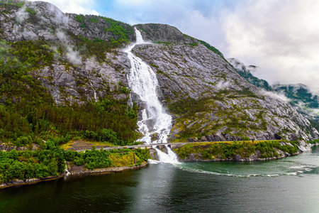 Western Norway. Langfossen cascade waterfall on the Vaule river. Passes through the highway. The photo was taken with a drone. Summer cold and rainy dayの写真素材