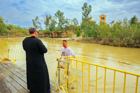 QASR El-YAHUD, ISRAEL - MARCH 2, 2020: Man in baptismal shirt comes out of the water of the Jordan River. Baptism ceremony. The site of the baptism of Jesus Christ. The concept of religious tourismのeditorial素材