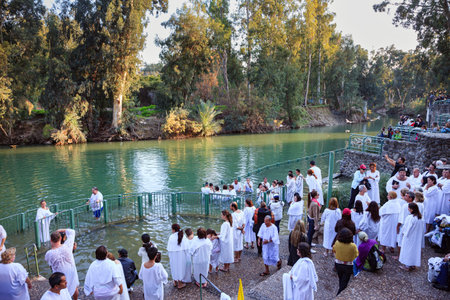 YARDENIT, ISRAEL - JANUARY 21, 2012: Group of believers in white baptismal shirts enter the waters of the Jordan River. Yardenit  the exit point of the Jordan River from Lake Kinneretのeditorial素材