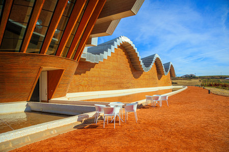 Winery - bodega Bodegas Ysios. Tables and chairs for tourists. Wave-shaped winery roof. Journey to the warm Spanish autumn. The sunset.の写真素材