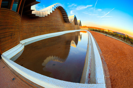 Laguardia. Fragment of the facade is reflected in the pool. Winery - bodega Bodegas Ysios. Bright flaming colors of the sunset. Journey to the warm Spanish autumnの写真素材