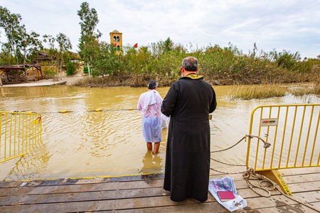 QASR EL YAHUD, ISRAEL - MARCH 2, 2020: Young man enters the water of the Jordan River. The site of the baptism of Jesus Christ in a historical place on the Jordan River.のeditorial素材