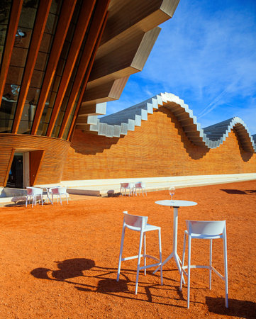 Table and chairs for tourists. Fragment of the facade. Winery - bodega Bodegas Ysios. Journey to the warm Spanish autumn. The sunset.の写真素材