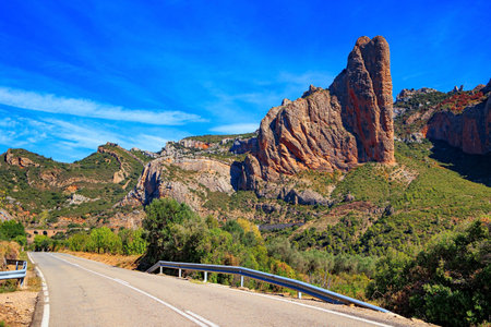 Asphalt highway passes through the rocks. The Mallets of Riglos. Part of the foothills of the Pyrenees. Hot sunny afternoon. Romantic trip to Spain. Aragon.の写真素材
