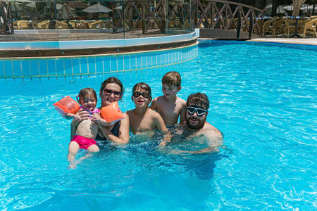 Parents and children oyfully swim, dive and laugh together. Family vacation in a hotel on the Greek island of Cyprus. Great swimming pool with clear water. Happy familyの写真素材
