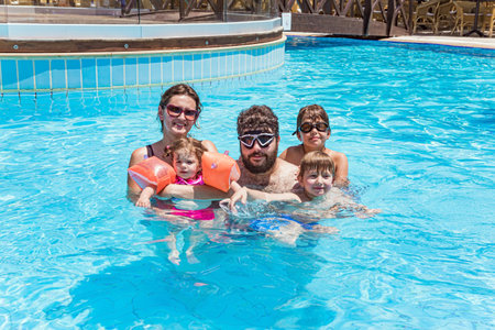 Children and parents joyfully swim, dive and laugh together. Family vacation in a hotel on the Greek island of Cyprus. Great swimming pool with clear water. Happy familyの写真素材