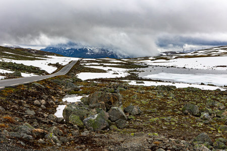Gray clouds and fog. Great "Snow Road". Huge cold snowfields and sharp stone placers. Cold July in Northern Europe. Journey to the fabulous northern country of Norway. "Bjorgavegen"の写真素材