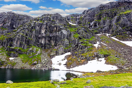 Traveling by camper on road 520. Cold summer in Norway. Large snowfields is reflected in the water of the lake. Light white clouds fly in the blue sky.の写真素材