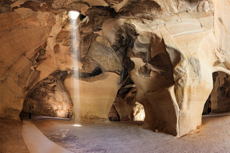 Sunbeam in the ceiling illuminates the vaults of the cave. Bell Caves - quarries of the 7th century AD. The walls of the cave amaze with a variety of rocks. The park Beit Guvrin, Israel.の写真素材