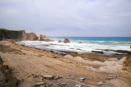Original rock ledges on the Playa de la Arnia beach. Cantabria, Spain. Picturesque coastal cliffs. Amazing geological formations amaze tourists.の写真素材