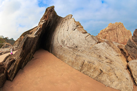 Woman in pink pants photographing a stunning landscape. Incredible rock formations, stones and boulders. Cantabria, Spain. The Playa de la Arnia beach.の写真素材