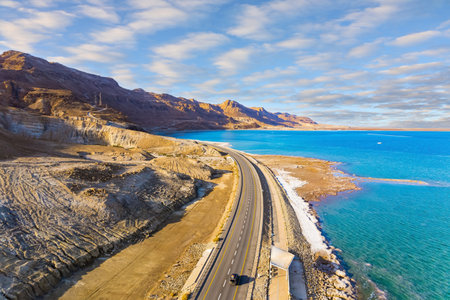 Sunset. Dead Sea photographed from a drone. Evaporated salt was deposited along the shore. Asphalt highway runs along the seashore. The winter in Dead Sea.の写真素材