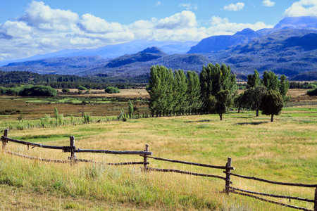Wooden fence crosses a field. Argentina. Fields and mountains surround the famous highway 40. Travel to South America. Charming rural pastoral.の写真素材