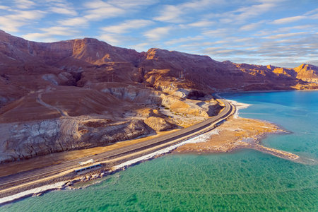Asphalt highway runs along the seashore. The winter in Dead Sea. Israel. Shallowed Dead Sea photographed from a drone. Evening twilight. Sunsetの写真素材