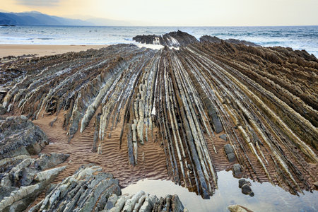 Playa Zumaya Basque country. Ocean low tide reveals picturesque ribbed underwater rocks. The Flysch. Itsurun Beach is surrounded by impressive geological formationsの写真素材