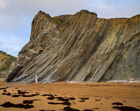 Flysch - underwater rocks exposed at low tide. Low tide in the Atlantic. Woman photographs Playa Zumaya. Low tide in the Atlantic.の写真素材