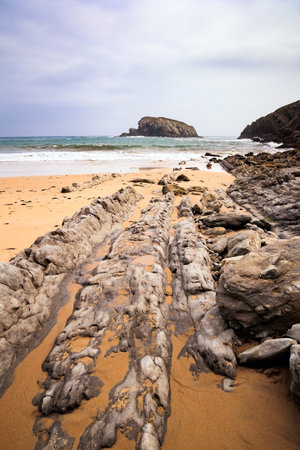 Interesting original rock ledges on the Playa de la Arnia beach. Cantabria, Spain. Amazing geological formations amaze tourists. Storm waves break on the coastal rocks.の写真素材