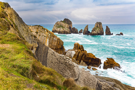 Stormy autumn day in the Bay of Biscay. The high surf crashes against the shore. Picturesque cliffs and huge stones oppose the ocean. Spanish coast. Portio beach. Atlantic Ocean.の写真素材