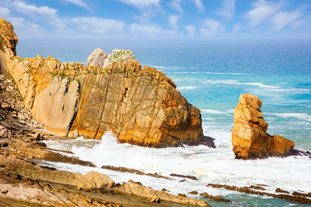 Cantabria, Spain. Playa de la Arnia beach. Amazing geological formations amaze tourists. Storm waves break on the coastal rocks. Snow-white sea foam glistens in the dim autumn sun.の写真素材