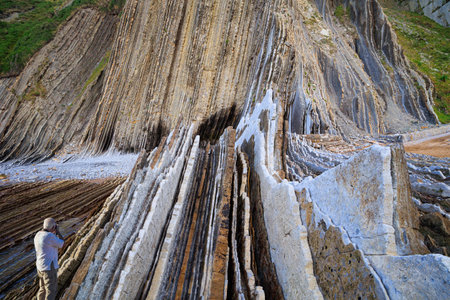 Tourist photographs a magnificent landscape. Playa Zumaya. Low tide in the Atlantic. Flysch - unique landscape of underwater rocks exposed at low tide. The Basque Country - Itsurun.の写真素材