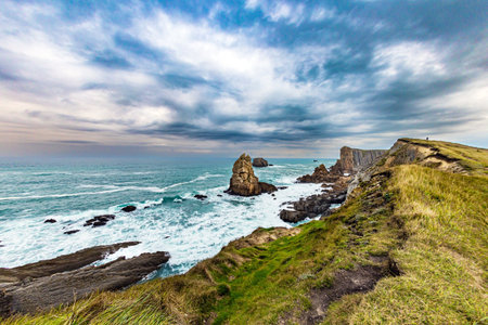 Portio beach. Rocky coastline of the Atlantic Ocean. Spanish coast, Cantabria. Stormy autumn day in the Bay of Biscay. Picturesque cliffs and huge stones oppose the ocean.の写真素材