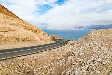 Magnificent paved highway along the seashore. The most salty sea on earth - Dead Sea. The Judean Desert is one of the most famous deserts in the world.  Israel, winter cloudy day.の写真素材