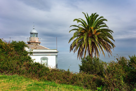 Snow-white lighthouse over the cliff. Candas. Atlantic coast, Spain. Part of the famous Costa Verde beach. Romantic trip to Spain. Mild autumn weather.の写真素材