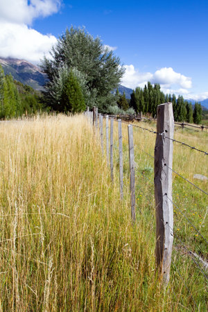 Wooden fence crosses a field. Fields and mountains surround the famous highway 40. Argentina. Travel to South America. Charming rural pastoral.の写真素材