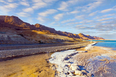 Dead Sea, Israel. Shallowed Dead Sea photographed from a drone. Evaporated salt was deposited along the shore. Asphalt highway runs along the seashore. Evening twilight. Sunsetの写真素材