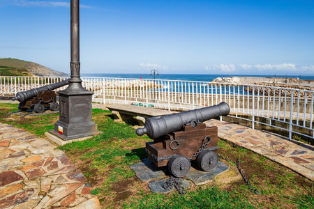 Antique cannons. The fishing port Luarca in the bay and moored pleasure yachts. Asturias, Atlantic coast. Romantic trip to Spain. Part of the famous Costa Verde beach.の写真素材