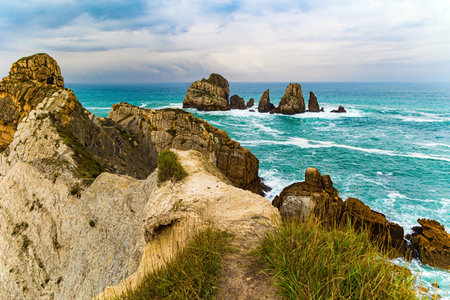 Stormy autumn day in the Bay of Biscay. Portio beach. Picturesque cliffs and huge stones oppose the ocean. Spanish coast, Cantabria. Rocky coastline of the Atlantic Ocean.の写真素材