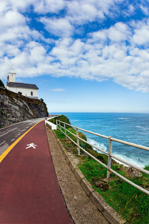 Beautiful road to Watchtower Chapel and Lighthouse. Unusual impressive architecture of the Luarca. The majestic Atlantic Ocean. Asturias. Romantic trip to Spain.の写真素材