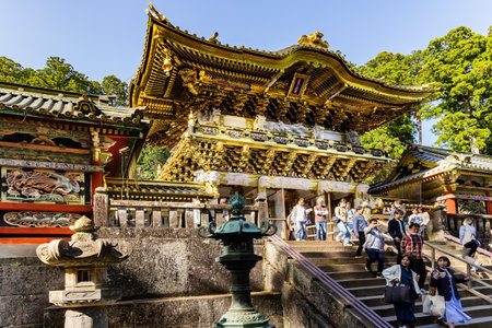 NIKKO, JAPAN, APRIL 22, 2023: Visitors to the temple and shrine of Nikko Tosho-gu. Sunset. Japan. Ornate temple with gilded roof. Building complex built in 1617.のeditorial素材