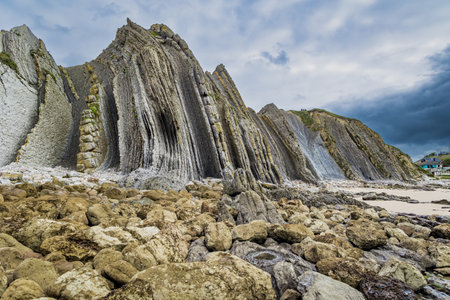 Portio Beach, Cantabria Beaches. Giant rough gray rocks and smooth sandy beach. Noon on the beach of Playa di Arnia, Spain. Windy stormy day on the Atlantic coast.の写真素材
